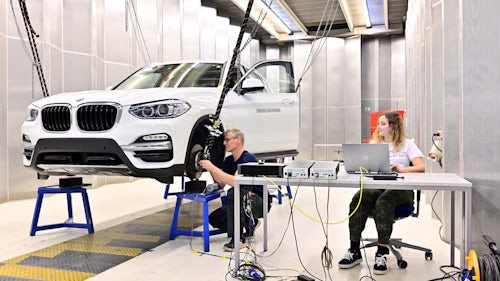 Two engineers working on a car in a workshop at the Leuven performance engineering facility.